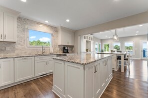 Una cocina amplia con armarios blancos, una isla grande y vistas al exterior.
