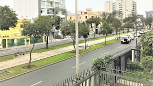 A city street with buildings, trees, and parked cars. - Hostal Carlos Tenaud  (Lima)