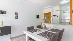 A modern dining area with a white table, four chairs, a decorative vase, and a clock on the wall. - 2 bedroom amazing apartment in Torrevieja (Torrevieja)