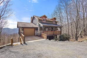 A two-story house with a stone foundation, a wooden deck, and a garage.