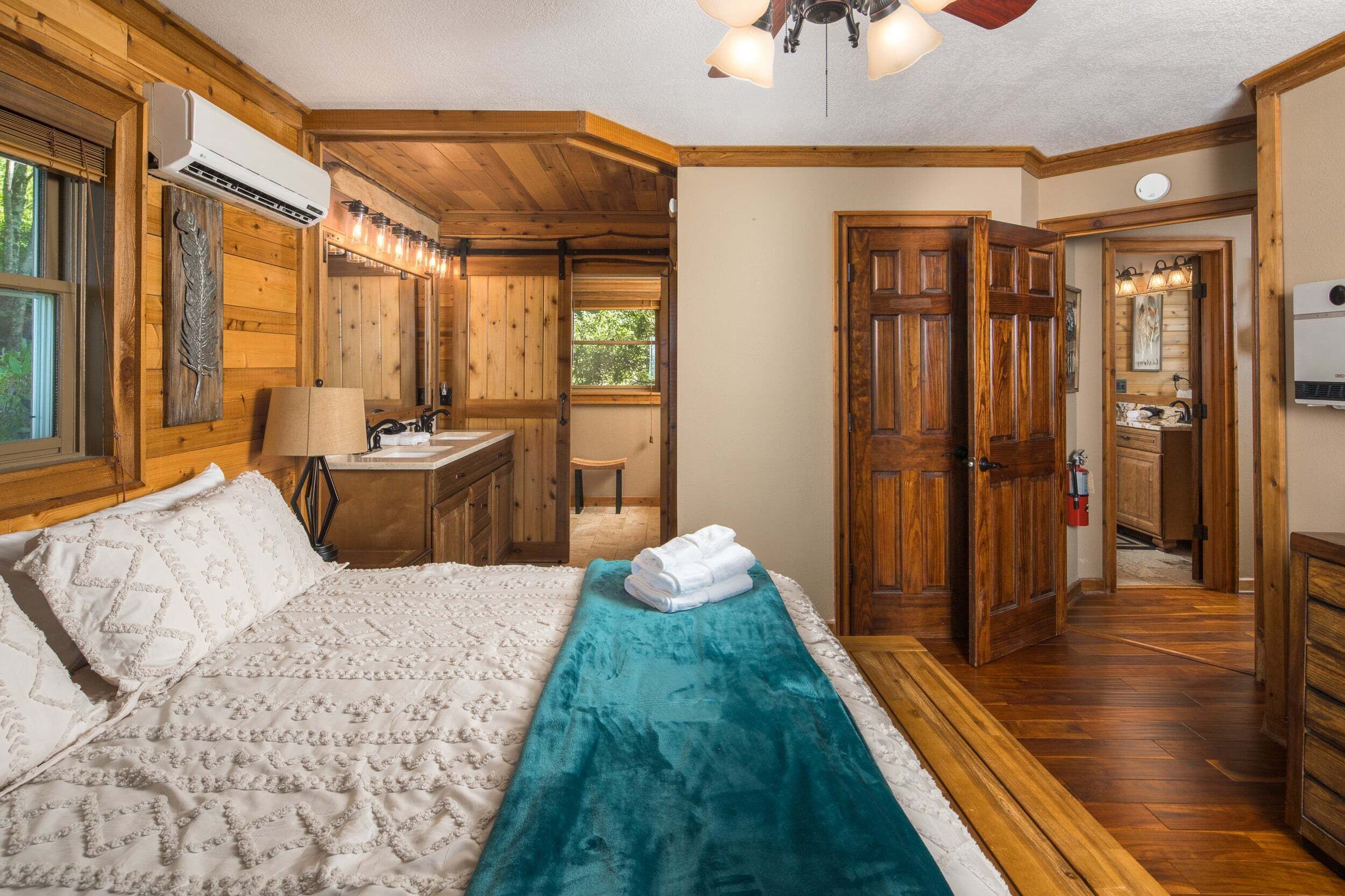 Ein schlicht eingerichtetes Schlafzimmer im Chalet-Stil mit Bett, einem Badezimmer und einem Flur, der in einen weiteren Raum führt.