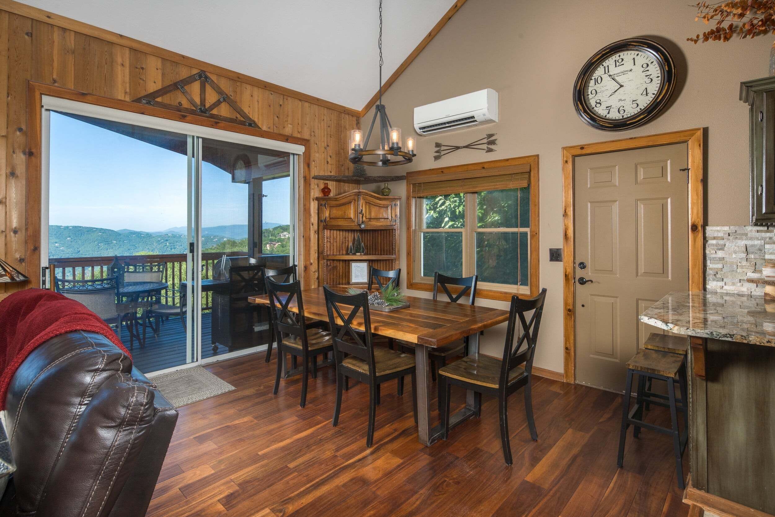 A dining area with a wooden table and chairs, a chandelier, and a view through glass doors.