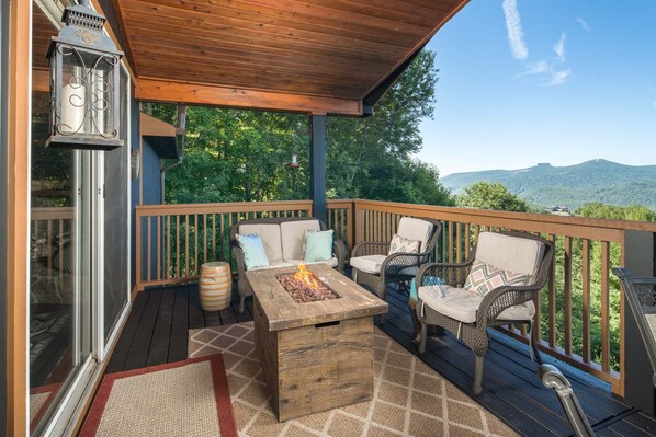 Un patio in legno con mobili da esterno, un braciere e una lanterna.