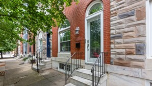 A row of brick townhouses with stone accents, a front door, and a small porch with steps.