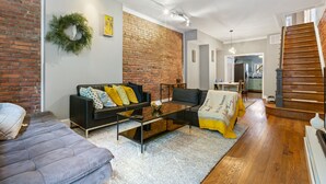 A living room with a brick wall, a sofa, a coffee table, and a staircase.