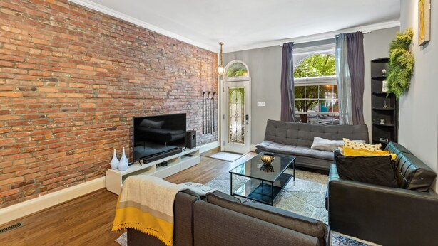 A living room with a brick wall, a flat-screen TV, a sofa, and a coffee table.