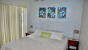 Une chambre à coucher avec un grand lit, deux tables de chevet et trois tableaux accrochés au mur.