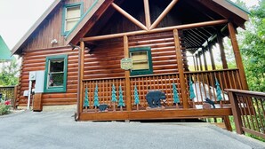 En stuga av trä med en veranda, en skylt med texten ”Utsikt över paradiset” och en björnstaty på räcket.
