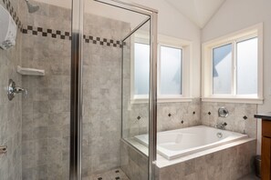 A modern bathroom with a glass-enclosed shower, a freestanding bathtub, and a window providing natural light.