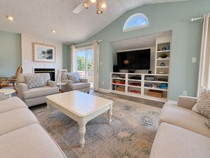 A living room with a fireplace, sofas, a coffee table, a TV, and a bookshelf.