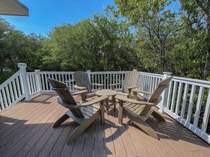 A wooden deck with a table and chairs, surrounded by white railings.