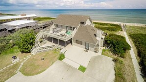 A two-story house with a large deck, a covered patio, and a view of the ocean.
