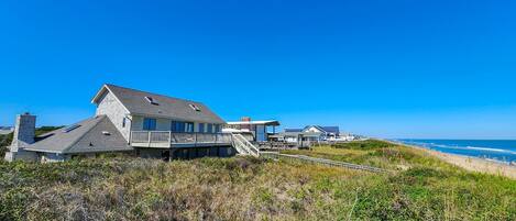 A beachfront property with a large house, a smaller building, and a pathway leading to the beach.