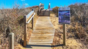 A wooden boardwalk leading to a beach area with a sign about sea turtle nesting season. - SALTY PAUSE - Enjoy vacation paradise on the sound side in the 4 BR home w/Private Pool (Southern Shores)
