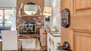 Een houten deur met een Yale-slot, een spiegel erboven en een lamp aan de muur.