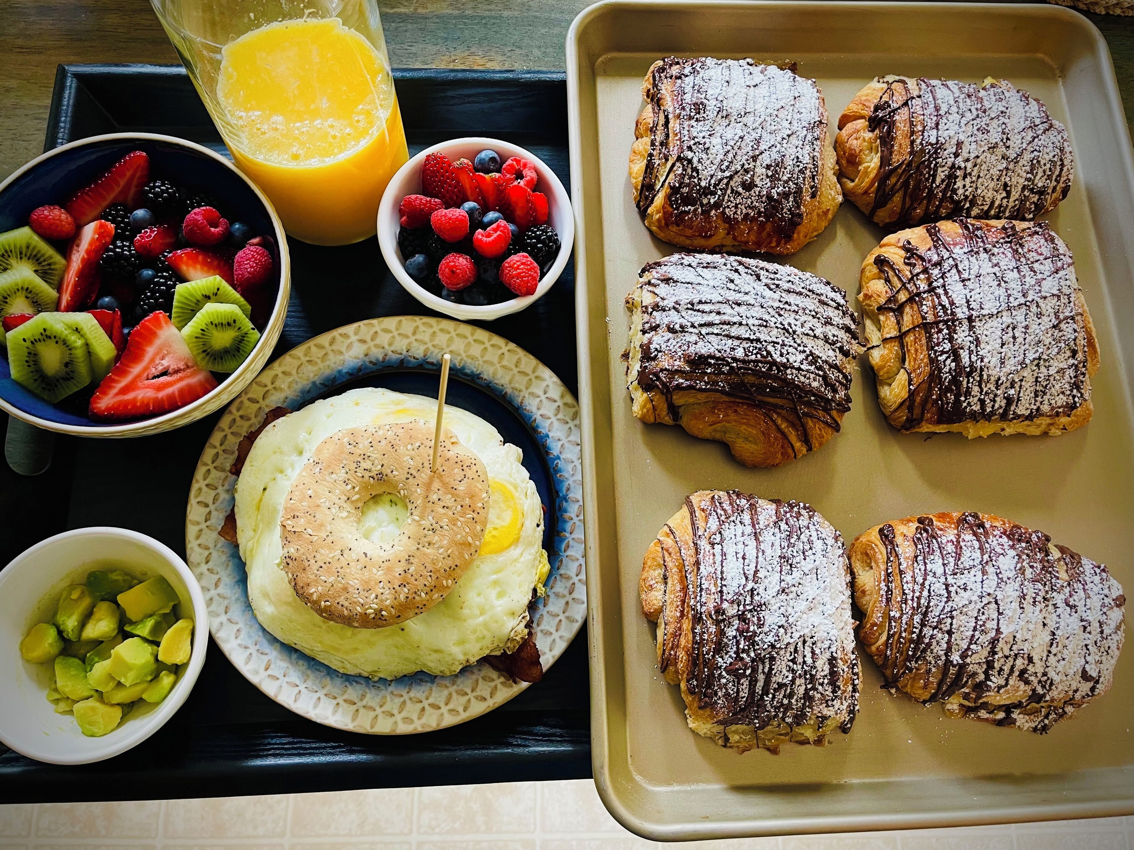Un plateau de petit-déjeuner avec des viennoiseries, des fruits et un verre de jus d’orange.