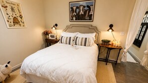 A bedroom with a large bed, a bedside table with a lamp, a framed picture on the wall, and a small rug. - Green Cottage Farm Stay & Food (Gardner)