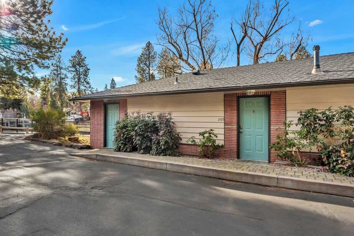 A single-story building with a garage door, a green door, and a brick facade.
