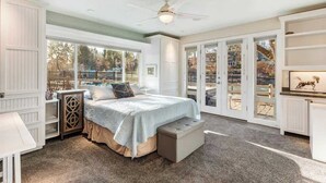 A bedroom with a bed, a bench, a nightstand, a dresser, and a ceiling fan. - Riverfront Cottage - Steam Room & Pet Friendly! (Bend)