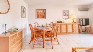 A dining area with a round table, four chairs, a wooden cabinet, a television, and a lamp. - Lovely apartment for 5 people with WIFI, A/C and balcony (Fréjus)