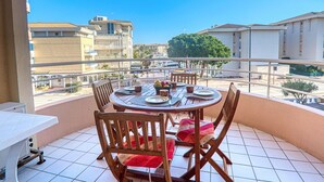 A balcony with a round table set for dining, wooden chairs, and a grill. - Lovely apartment for 5 people with WIFI, A/C and balcony (Fréjus)