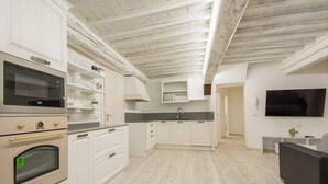Eine moderne Küche mit weißen Schränken, einem eingebauten Ofen und einer grauen Arbeitsplatte.