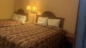 A hotel room with a double bed, two bedside lamps, a nightstand with a telephone, and a patterned bedspread. - Economy INN poteau (Poteau)