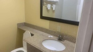 A small bathroom with a toilet, sink, and mirror. - Economy INN poteau (Poteau)
