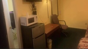A hotel room with a flat-screen TV mounted on the wall, a microwave on a small table, a desk with a chair, and a trash bin. - Economy INN poteau (Poteau)