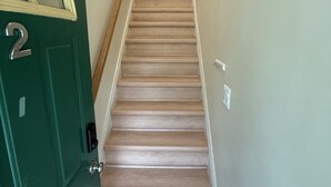 Un escalier recouvert de moquette, avec une porte verte sur le côté gauche, qui mène à un espace intérieur.