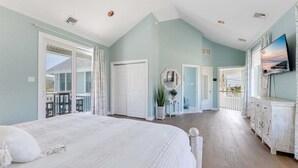 Ein Schlafzimmer mit einem großen Bett, einem Fernseher, einem Balkon und Meerblick.