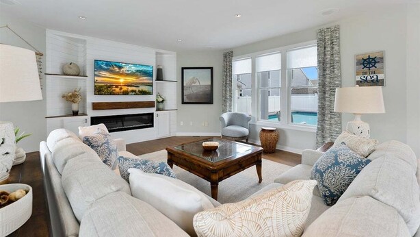 Ein Wohnzimmer mit einer Sofagarnitur, einem Couchtisch, einem Kamin, einem Fernseher und Meerblick.