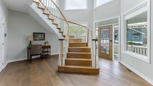Eine Treppe mit Holzboden und weißen Geländern, die zu einer Zwischenebene mit einer Tür führt.