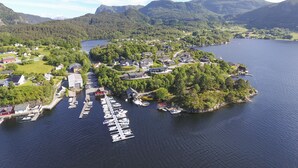 An aerial view of a lakeside village with houses, a marina, and surrounding mountains. - Tysnes Norway by Luxury Mountain Destina (Tysnes)