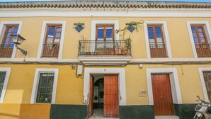 Un edificio giallo con una porta in legno e un balcone.