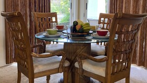 Un coin repas avec une table ronde, quatre chaises en bois et une variété de fruits et de bols.