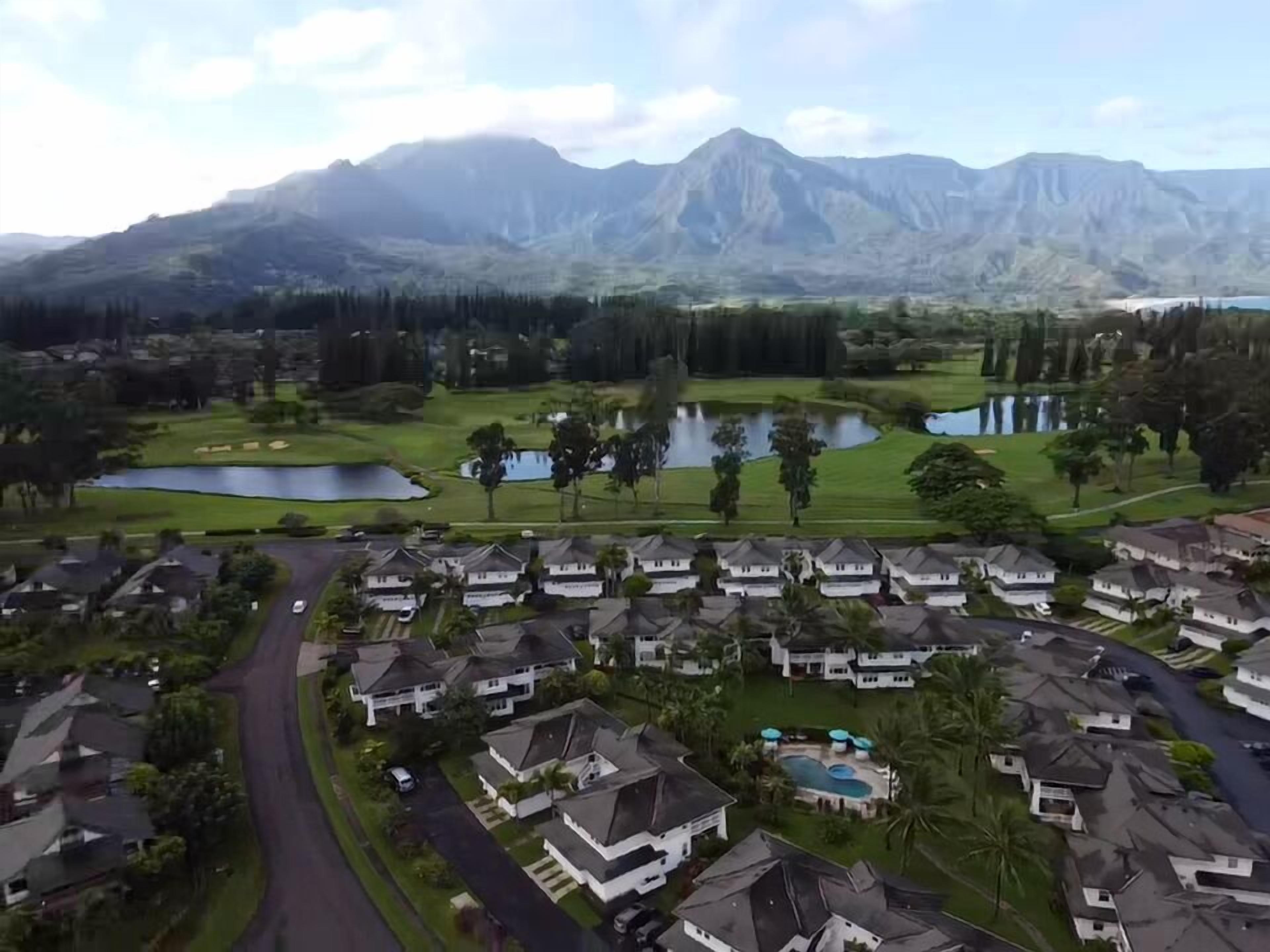 A residential area with houses, a golf course, and a mountain range in the background.