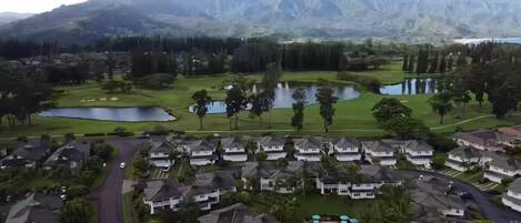 A residential area with houses, a golf course, and a mountain range in the background.