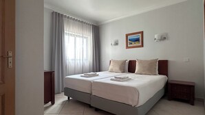 A double bed with two pillows, a nightstand, a wall-mounted light, and a framed picture on the wall. - Oceanview Bliss in Albufeira Retreat Over Oldtown (Albufeira)