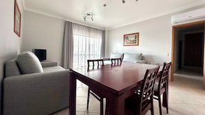 A modern living room with a dining table, sofa, and TV. - Oceanview Bliss in Albufeira Retreat Over Oldtown (Albufeira)