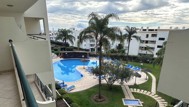 A pool area with blue water, surrounded by lounge chairs and palm trees. - Oceanview Bliss in Albufeira Retreat Over Oldtown (Albufeira)