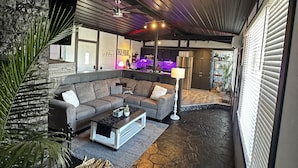 A modern living room with a stone floor, a sectional sofa, and a coffee table. - Cozy Cove with Beach, Dock, and Indoor Sauna (Sunrise Beach)