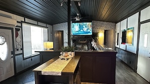 A modern kitchen with a wooden island, built-in appliances, and a stone fireplace. - Cozy Cove with Beach, Dock, and Indoor Sauna (Sunrise Beach)