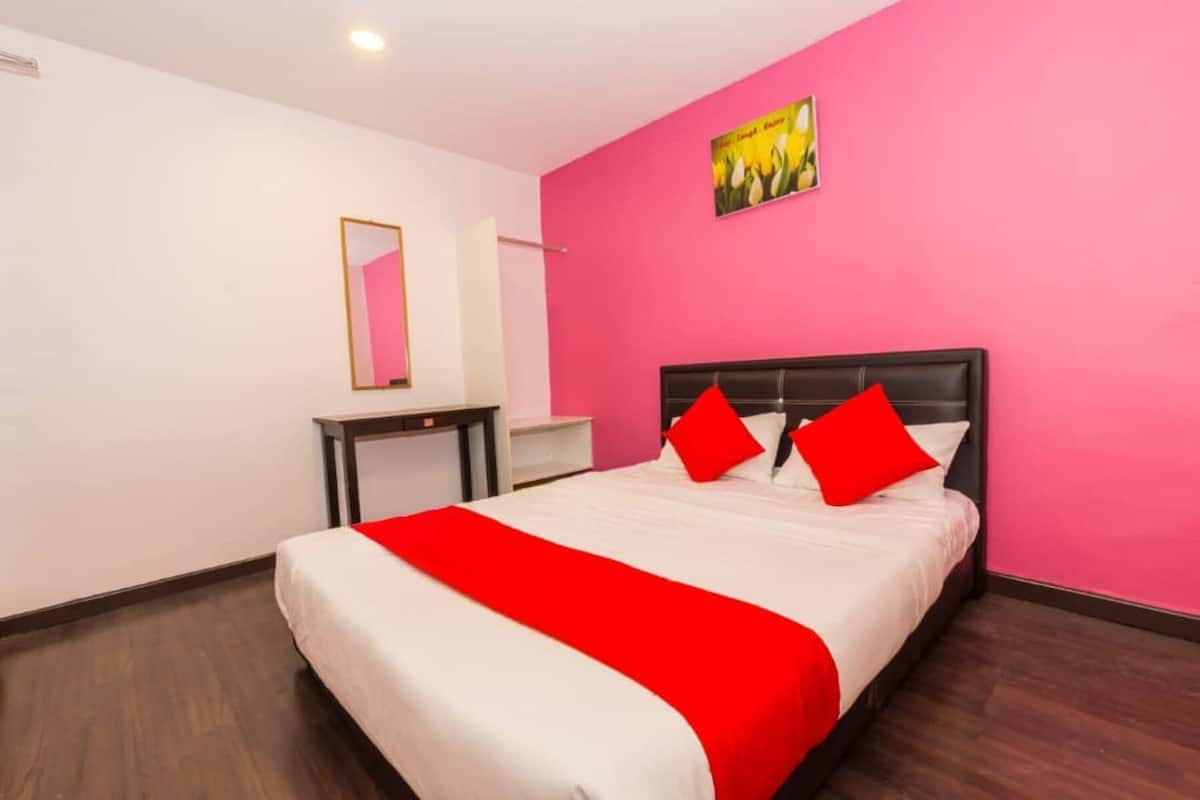 Een hotelkamer met een groot bed, een nachtkastje, een spiegel en een roze muur.