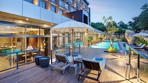 A modern hotel with a pool area, lounge chairs, and a dining area with a view of the pool. - Sima Sumba Hotel (Tambolaka)