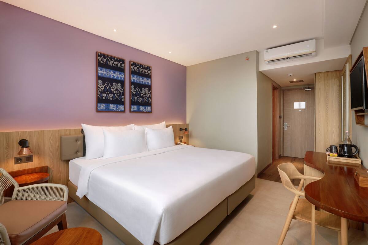Hotelkamer met een groot bed, een bureau met stoel, een televisie en een airconditioning.