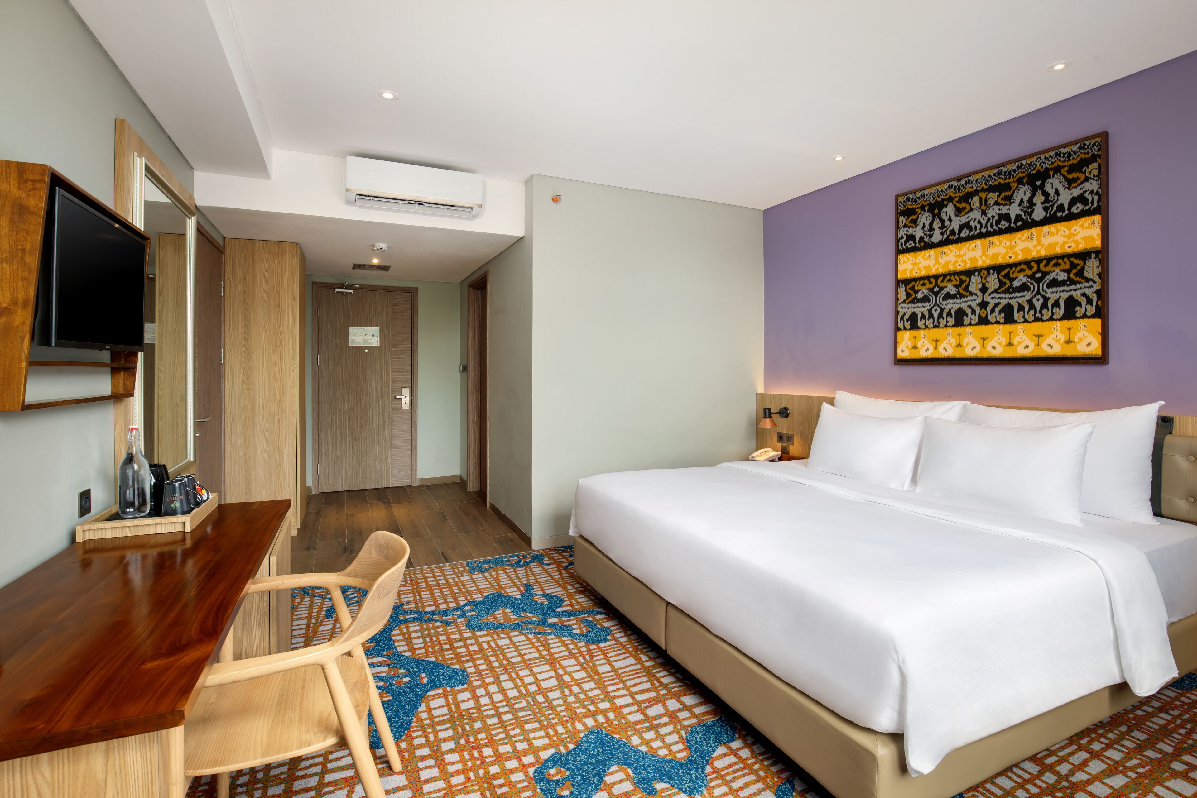 A hotel room with a bed, a desk, a chair, and a television.