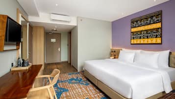 A hotel room with a bed, a desk, a chair, and a television.