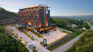 A modern hotel with a multi-story structure, a spacious parking area, and a view of the surrounding landscape. - Sima Sumba Hotel (Tambolaka)