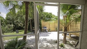 A patio area with a view of a garden, a wooden fence, and a grill. - Pet friendly beach house w/private backyard & outdoor shower- steps from beach (St. Augustine)
